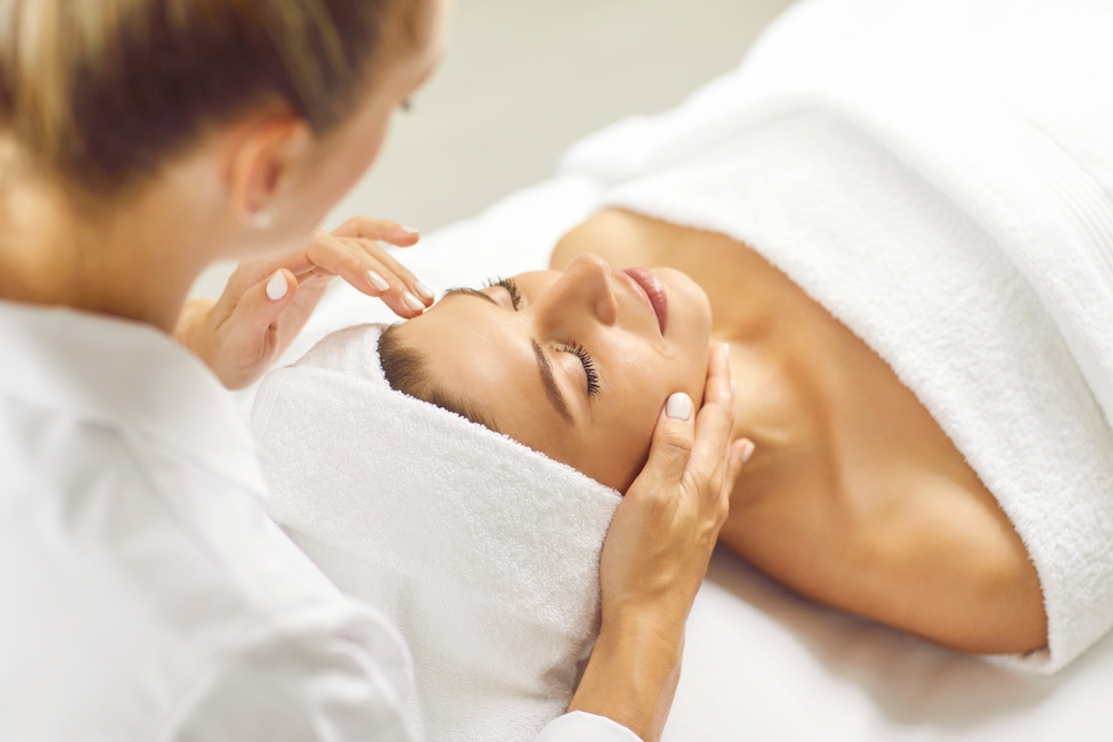 Beautiful woman with closed eyes relaxes in spa center during facial massage.