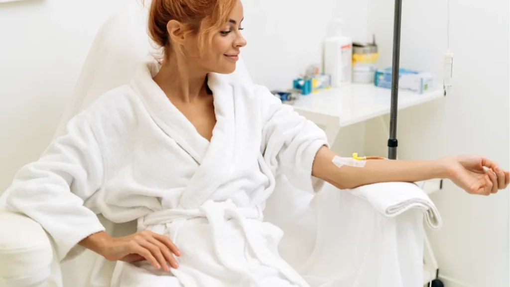 Portrait of mindful woman sitting in armchair and closed eyes while receiving IV infusion with vitamins. Cosmetology and medicine concept