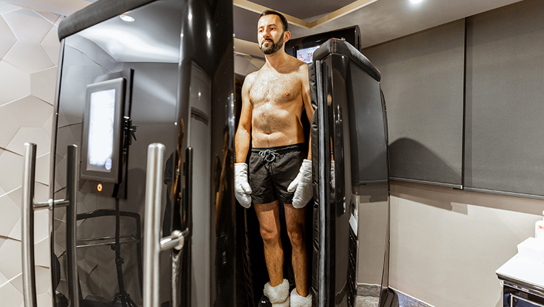 Man taking cryotherapy treatment, standing at the capsule door at a Spa salon